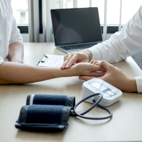 The man doctor measures the wrist pulse, the heartbeat of the patient, and discusses health care closely. Medical and health care concepts.